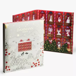 Calendrier de l'Avent DAMMANN - 2025 illustré par Arnold d'Alger, montrant un hôtel de montagne enneigé et un assortiment de 25 sachets de thé Cristal®.